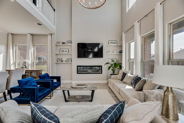 living room featuring a towering ceiling, light hardwood / wood-style floors, and a notable chandelier