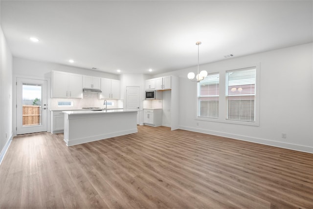 kitchen with built in microwave, decorative light fixtures, light wood-type flooring, a notable chandelier, and white cabinets