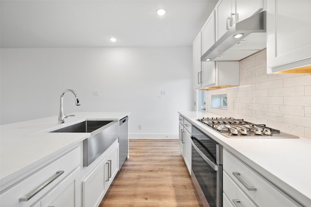 kitchen with white cabinets, decorative backsplash, sink, and appliances with stainless steel finishes