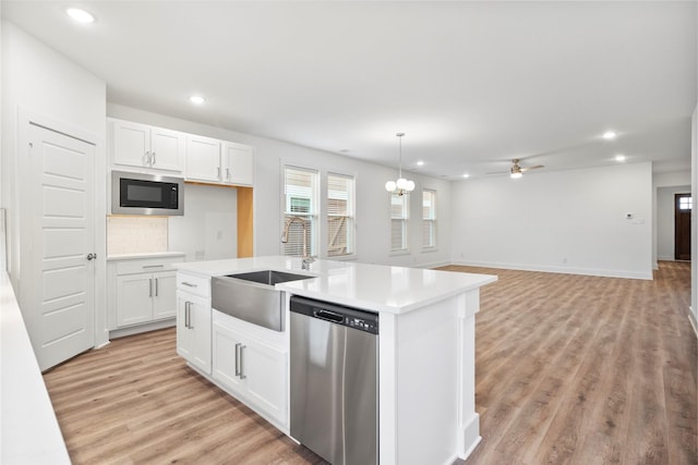 kitchen featuring white cabinetry, pendant lighting, stainless steel dishwasher, and built in microwave