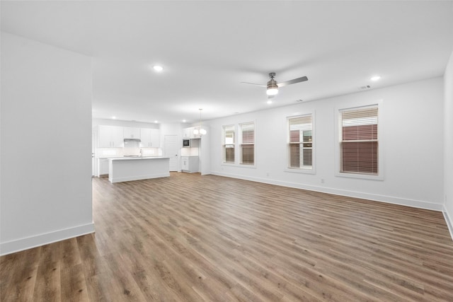 unfurnished living room with ceiling fan and dark wood-type flooring