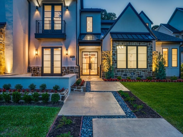 doorway to property with a yard, a balcony, and french doors