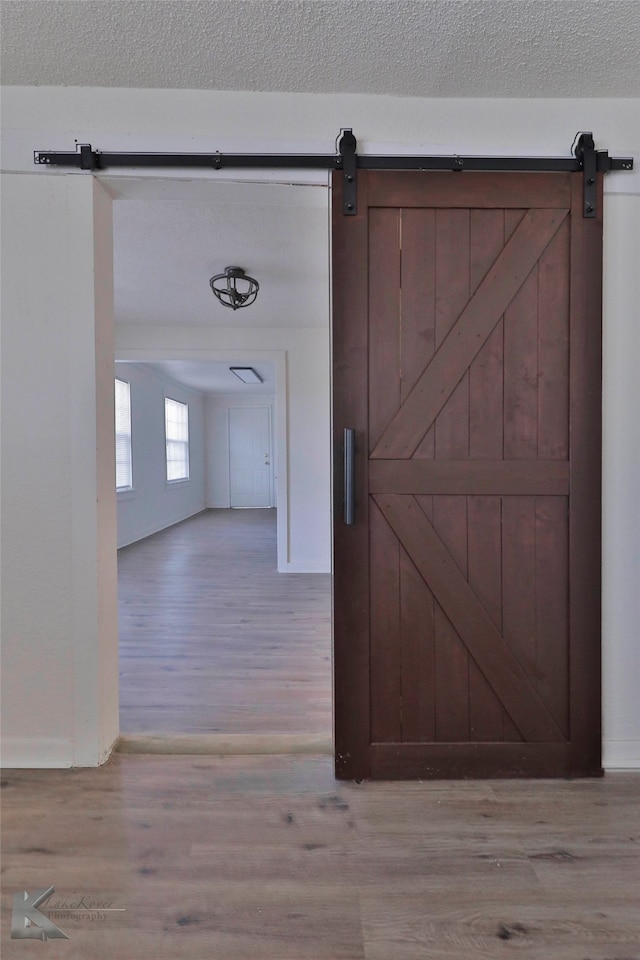 hallway featuring hardwood / wood-style floors, a barn door, and a textured ceiling