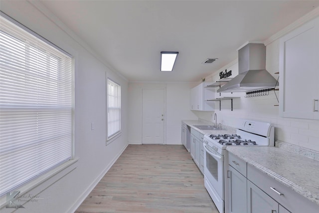 kitchen featuring light wood-type flooring, white gas range, light stone counters, extractor fan, and sink