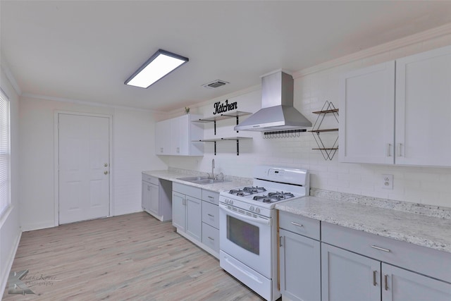 kitchen featuring white gas stove, exhaust hood, tasteful backsplash, and light hardwood / wood-style flooring