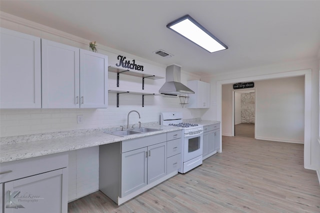 kitchen featuring light hardwood / wood-style flooring, tasteful backsplash, white range with gas cooktop, and wall chimney exhaust hood