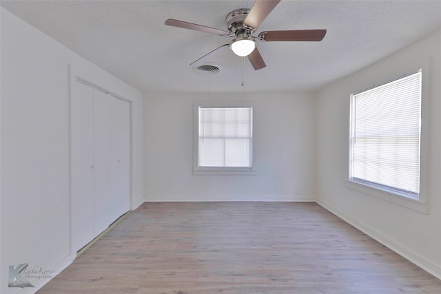 spare room with a textured ceiling, ceiling fan, and light wood-type flooring