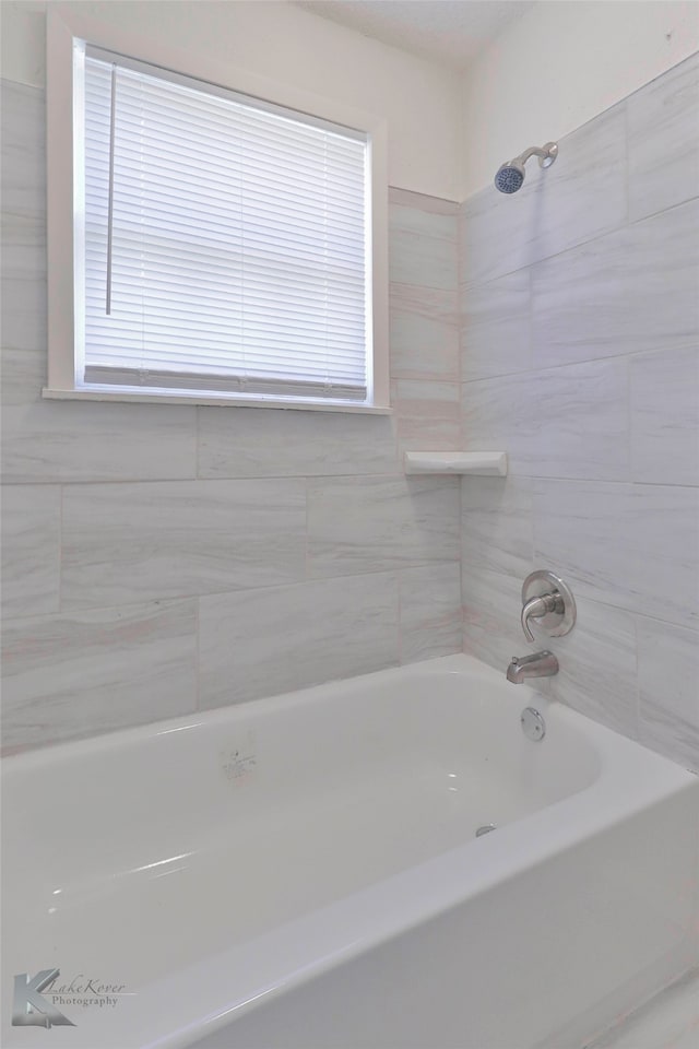 bathroom with a wealth of natural light and tiled shower / bath combo