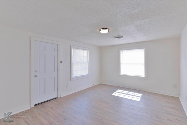 unfurnished room featuring light hardwood / wood-style flooring and a textured ceiling