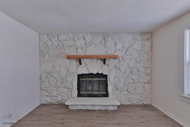 unfurnished living room with a stone fireplace, a healthy amount of sunlight, hardwood / wood-style flooring, and a textured ceiling