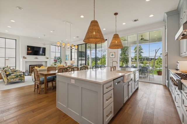 kitchen featuring plenty of natural light, a center island with sink, decorative light fixtures, sink, and hardwood / wood-style flooring