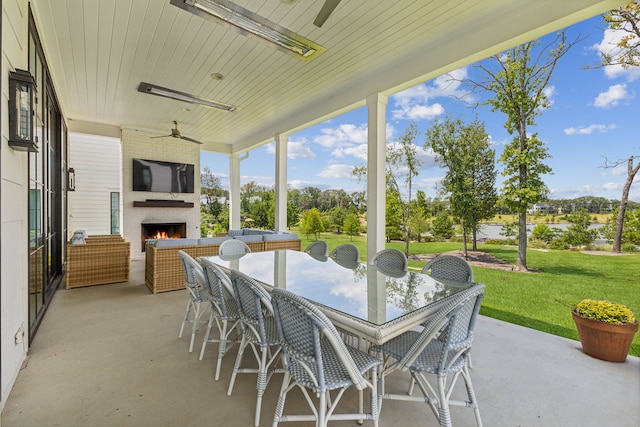 sunroom featuring ceiling fan and an outdoor fireplace