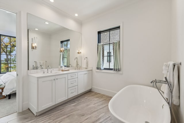 bathroom featuring a bath, vanity with extensive cabinet space, crown molding, and double sink