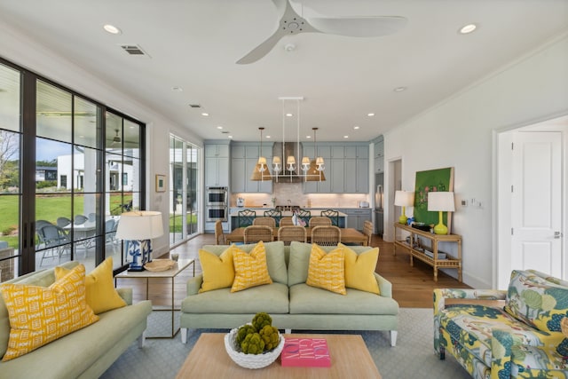 living room featuring hardwood / wood-style floors, ceiling fan, and crown molding