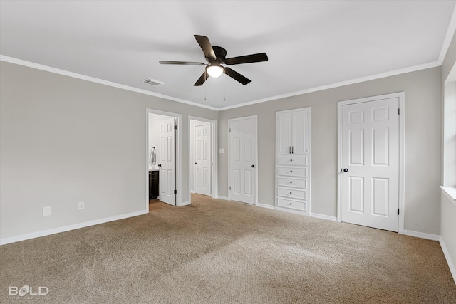 unfurnished bedroom featuring ceiling fan, multiple closets, crown molding, and carpet