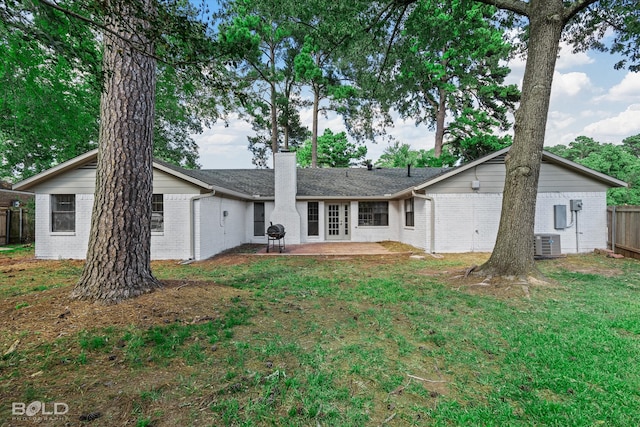 rear view of property with a lawn, a patio, and central AC