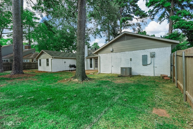 back of property with a lawn and central AC