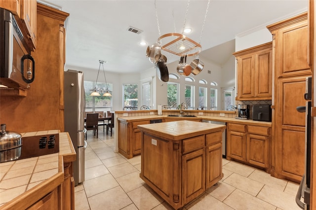 kitchen with a wealth of natural light, tile countertops, appliances with stainless steel finishes, and a kitchen island