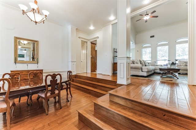 dining area with ornate columns, wood-type flooring, ceiling fan with notable chandelier, and crown molding