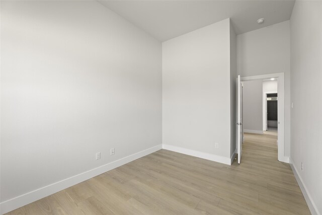 unfurnished room featuring a towering ceiling and light hardwood / wood-style floors