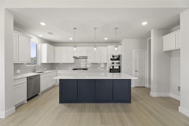 kitchen featuring light wood-type flooring, a center island, decorative backsplash, and stainless steel appliances