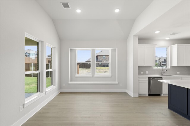 kitchen with backsplash, light hardwood / wood-style flooring, stainless steel dishwasher, white cabinets, and vaulted ceiling