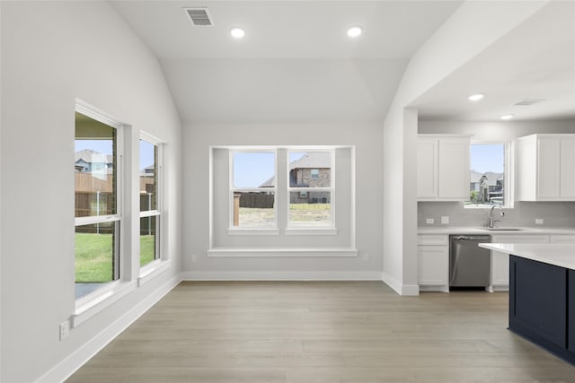 kitchen featuring white cabinetry, stainless steel dishwasher, lofted ceiling, and sink