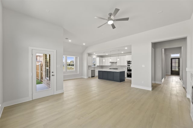 unfurnished living room with ceiling fan, light wood-type flooring, and lofted ceiling