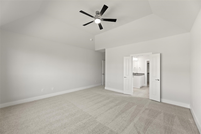 unfurnished bedroom with ceiling fan, ensuite bath, light carpet, and lofted ceiling