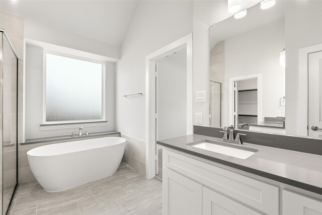 bathroom featuring vaulted ceiling, a bath, vanity, and tile patterned floors