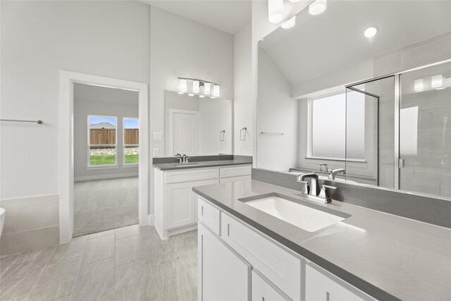 bathroom featuring dual vanity, tile patterned flooring, and lofted ceiling