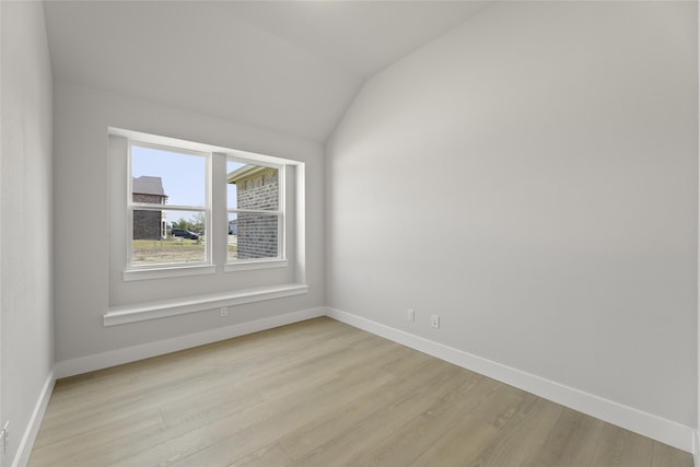 spare room with light hardwood / wood-style floors and lofted ceiling