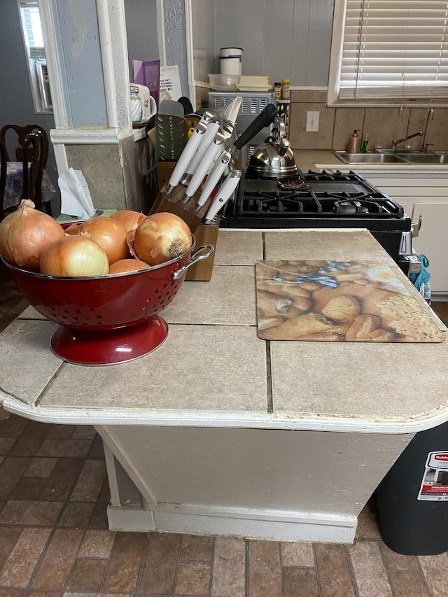 kitchen featuring gas range oven, backsplash, and sink