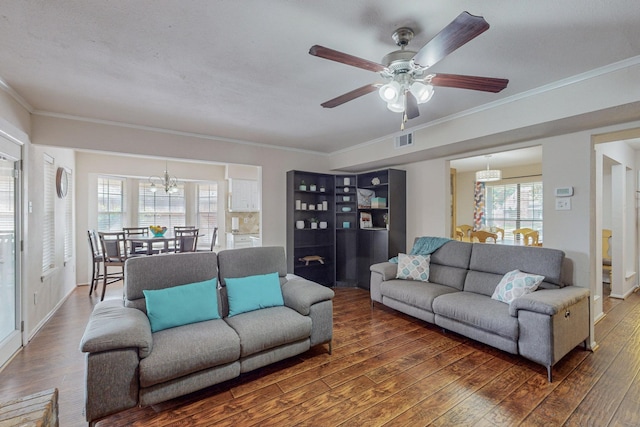 living room featuring ceiling fan with notable chandelier, ornamental molding, and dark wood-type flooring