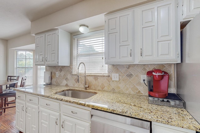 kitchen featuring light stone countertops, sink, white cabinets, and stainless steel dishwasher