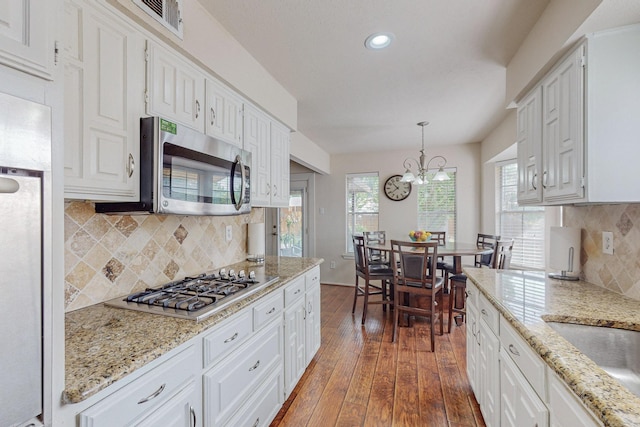 kitchen with decorative light fixtures, dark hardwood / wood-style flooring, stainless steel appliances, and white cabinetry