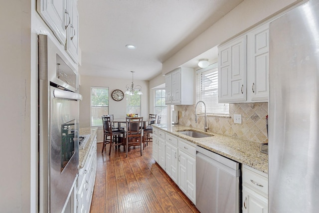 kitchen with pendant lighting, sink, white cabinets, and stainless steel appliances