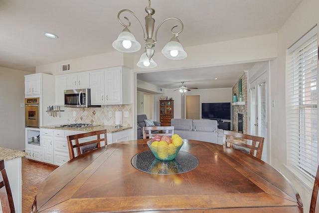 dining room with ceiling fan with notable chandelier and hardwood / wood-style flooring