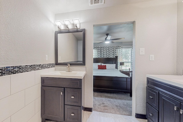 bathroom featuring ceiling fan, vanity, and tile walls