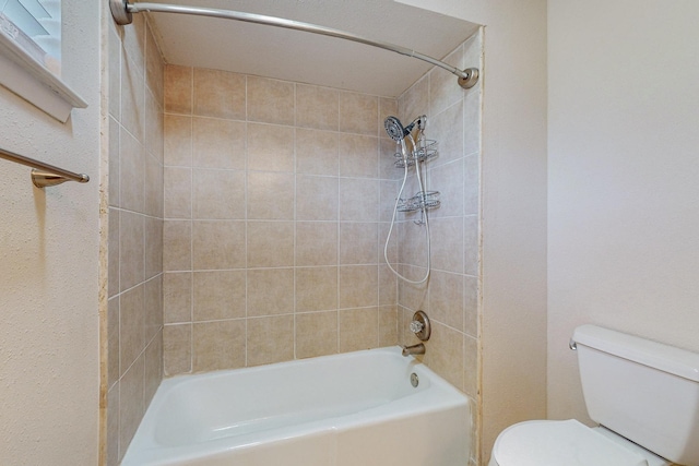 bathroom featuring tiled shower / bath combo and toilet