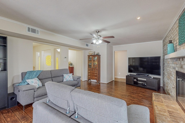 living room featuring ceiling fan, ornamental molding, dark wood-type flooring, and a brick fireplace