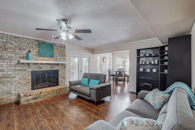 living room with a brick fireplace, ornamental molding, a textured ceiling, ceiling fan, and dark hardwood / wood-style floors