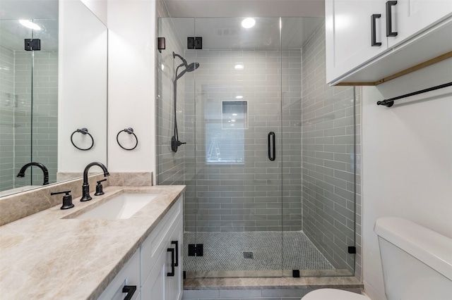 bathroom with a shower with shower door, toilet, and large vanity