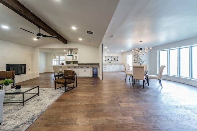 living room featuring dark hardwood / wood-style flooring, beverage cooler, ceiling fan with notable chandelier, lofted ceiling with beams, and a high end fireplace