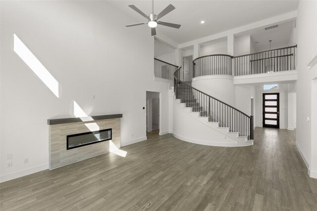 5241 Great Hollow Trl, Fort Worth, TX 76179 - unfurnished living room featuring a towering ceiling, stairway, ceiling fan, a tiled fireplace, and baseboards