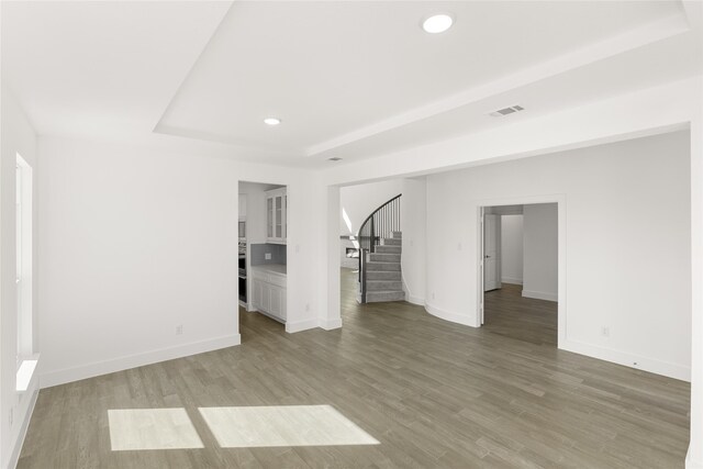 5241 Great Hollow Trl, Fort Worth, TX 76179 - spare room featuring stairs, baseboards, light wood finished floors, recessed lighting, and a raised ceiling