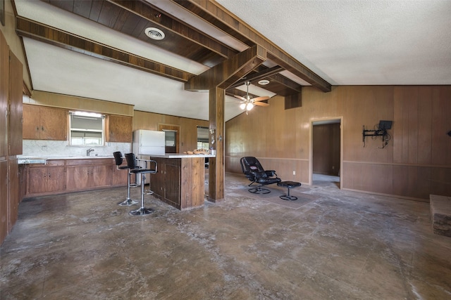 kitchen with white fridge, ceiling fan, a kitchen bar, lofted ceiling with beams, and a textured ceiling