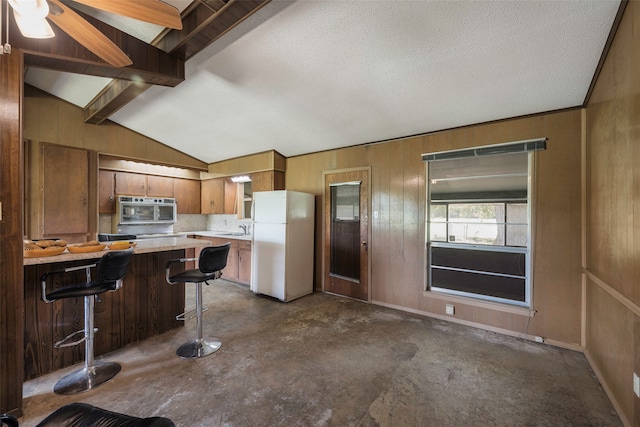 kitchen featuring a textured ceiling, lofted ceiling with beams, white refrigerator, ceiling fan, and a kitchen bar