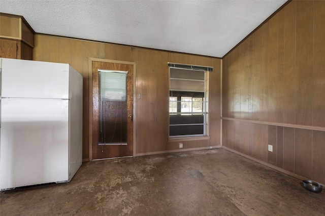 interior space with a textured ceiling, wooden walls, and white refrigerator