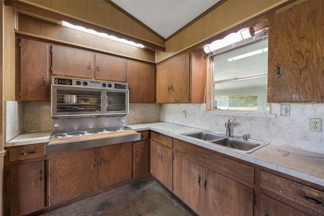 kitchen with stovetop, sink, vaulted ceiling, and tasteful backsplash